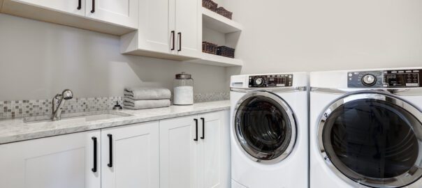 A modern-looking laundry room with black accents and white appliances and cabinets