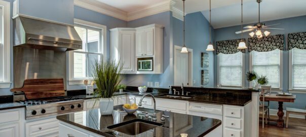 An image of a modern kitchen with blue walls, white cabinetry, and charcoal granite countertops.