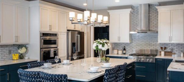A modern kitchen with white and dark blue cabinets that have silver handles.