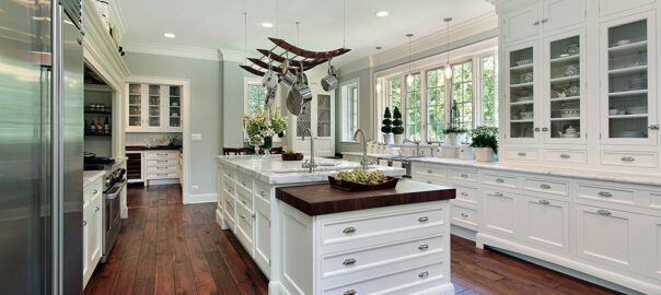 a kitchen with hardwood floors and white cabinetry, some with glass doors