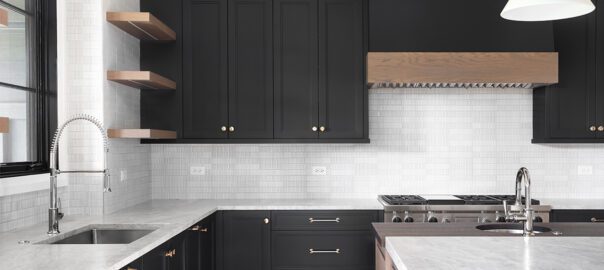 A modern kitchen with granite countertops, black cabinetry, and gold hardware.