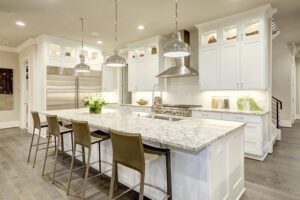A white kitchen with statement pieces and art pieces behind glass cases above the cabinetry