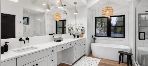a white bathroom with black hardware, wooden floors, and unique lighting