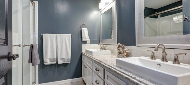 a bathroom with granite counters and gray walls