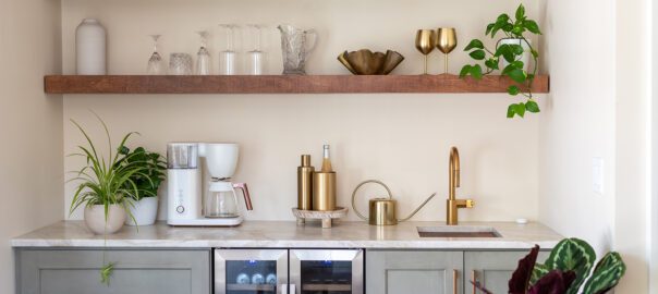 A kitchen scene with floating shelves where glasses, décor, and pitchers are resting.